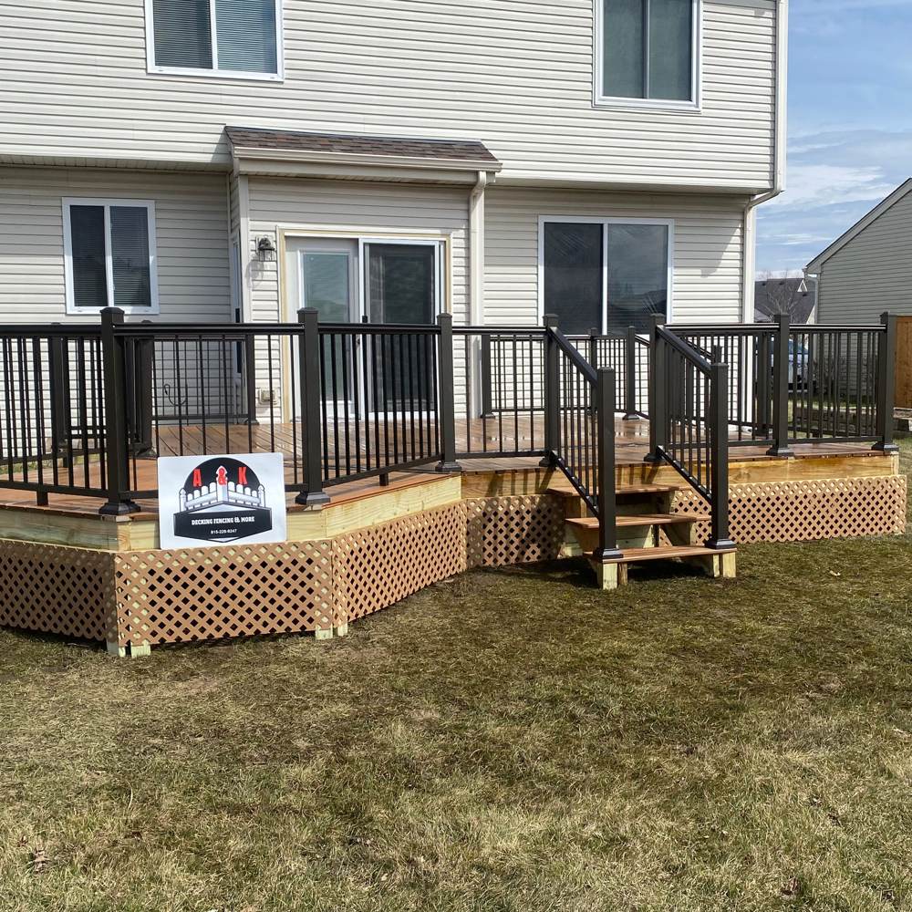 Two-tier composite deck with black railings and the A&K yard sign